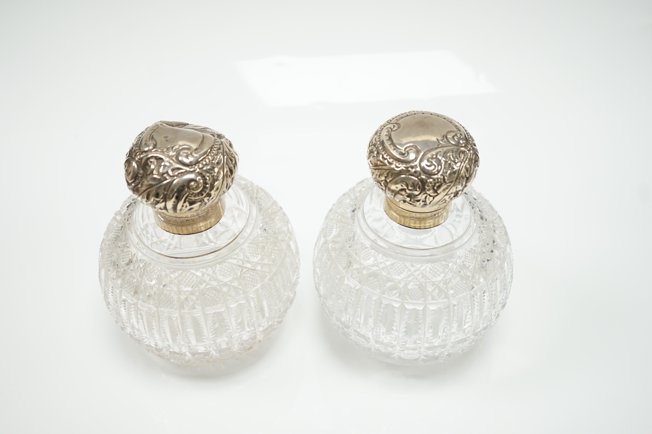 A pair of late Victorian silver mounted cut glass globular scent bottles (a.f.), Haseler Brothers, Birmingham, 1894/5, height 14.9cm.